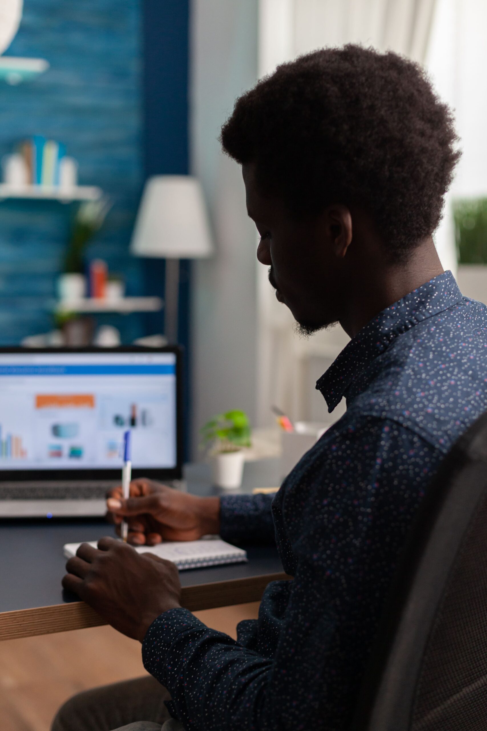 black-student-writing-financial-strategy-notebook-working-business-presentation-using-laptop-computer-living-room-teenager-having-online-school-coronavirus-lockdown (1)